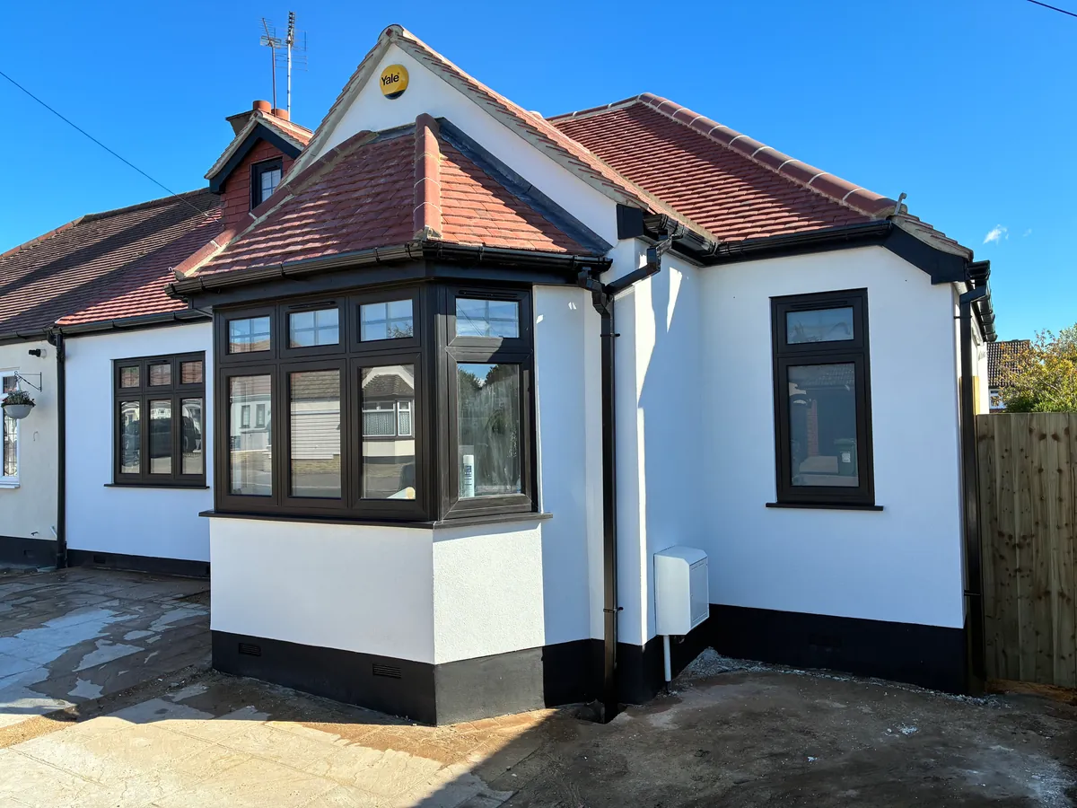 Angled view of the white-rendered bungalow and its black-framed bay window