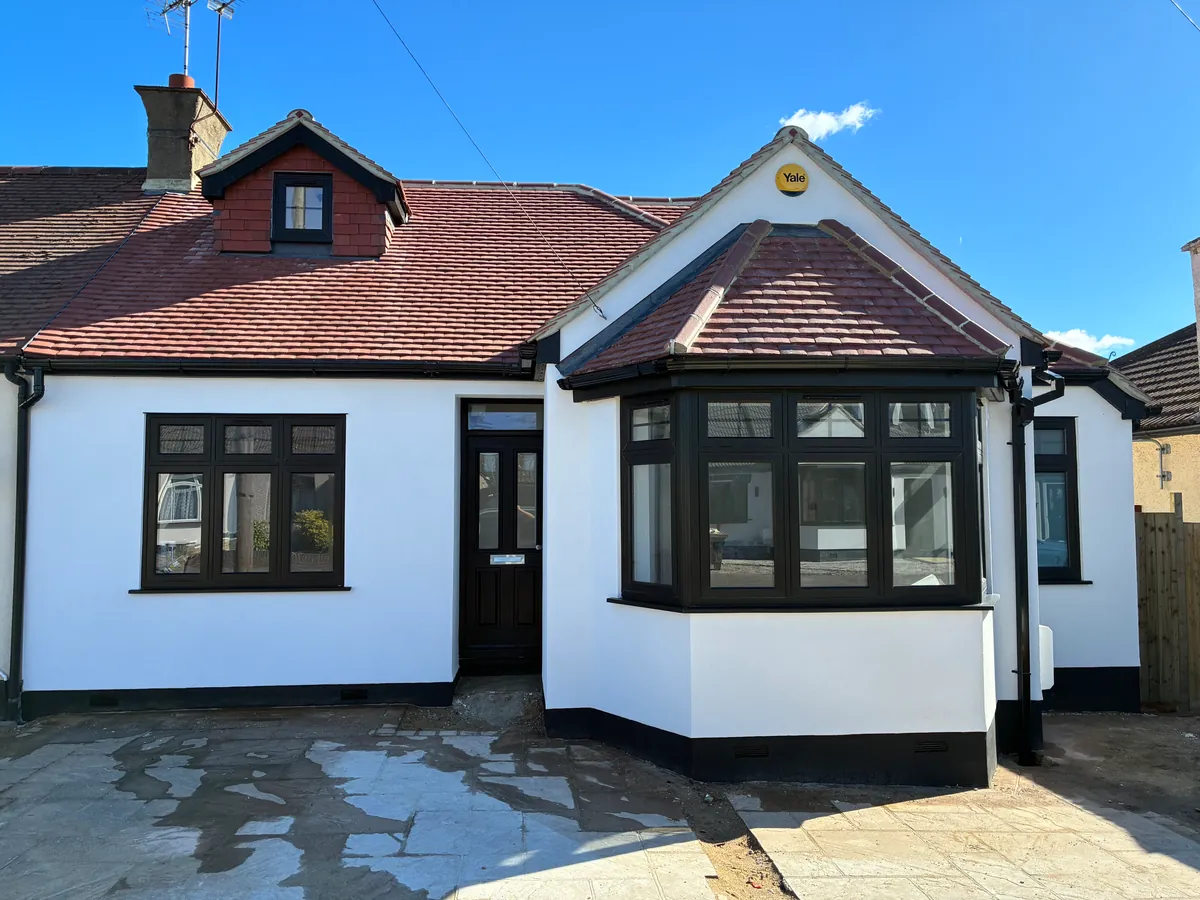 White-rendered bungalow front with black windows and a red tiled roof